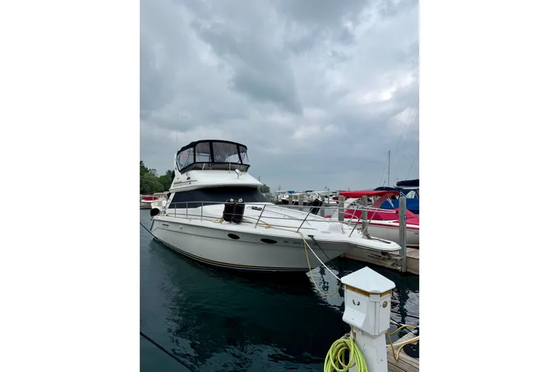 The Image of 1995 Sea Ray 370 Sedan Bridge yacht docked at marina under cloudy sky. - 2