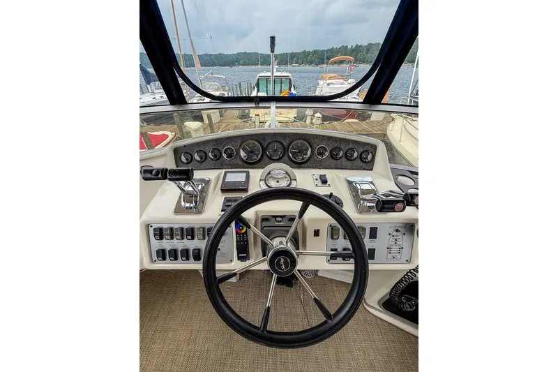 Slide: The Image of 1995 Sea Ray 370 Sedan Bridge helm with steering wheel and control panel, docked by the water. - 30