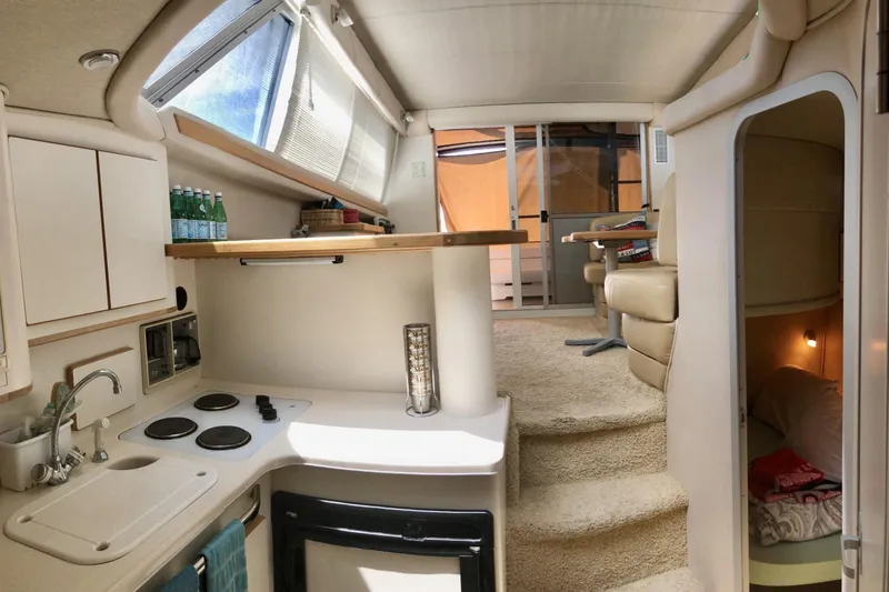 Slide: The Image of Interior of 1996 Sea Ray 370 Sedan Bridge yacht, featuring kitchen and cozy seating area. - 7