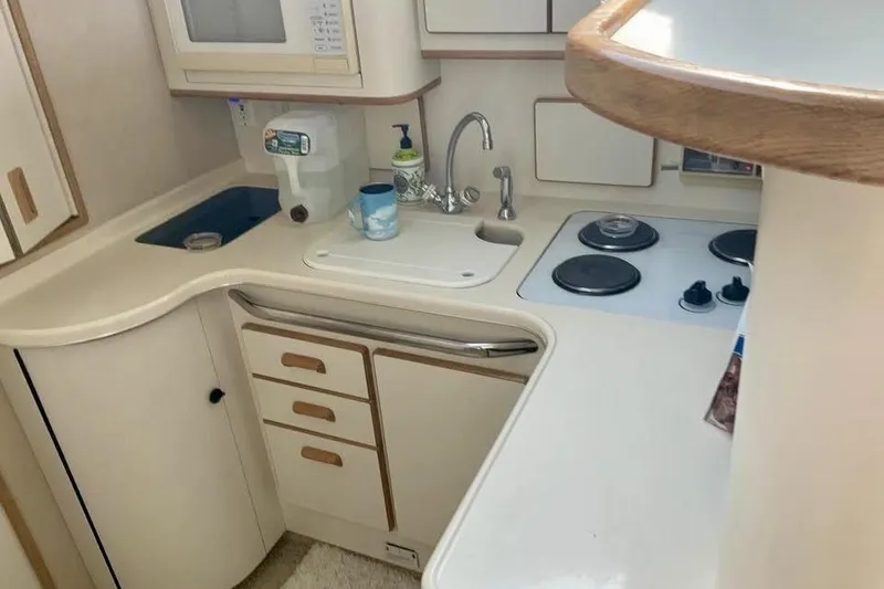 Slide: The Image of 1996 Sea Ray 370 Sedan Bridge kitchen with stove, sink, and microwave. - 8