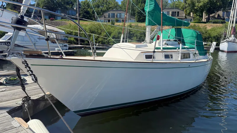 Slide: The Image of 1981 Sabre 28 sailboat docked, featuring green sail covers and sleek white hull. - 29