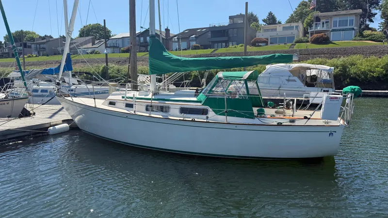 Slide: The Image of 1981 Sabre 28 sailboat docked at marina, featuring green sail cover and clear skies. - 30