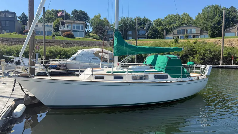 Slide: The Image of 1981 Sabre 28 sailboat docked at marina, surrounded by greenery and residential homes. - 31