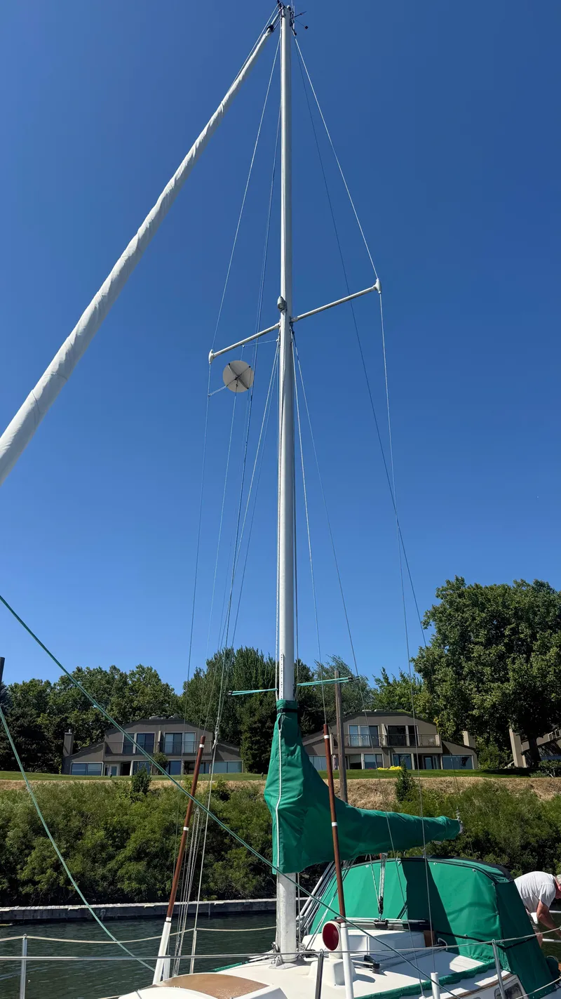 Slide: The Image of 1981 Sabre 28 sailboat with tall mast, green covers, docked under clear blue sky. - 34