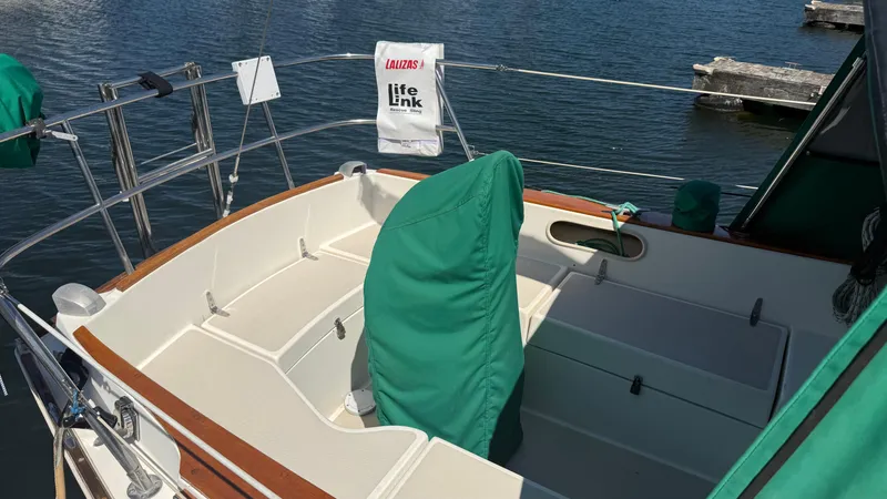 Slide: The Image of 1981 Sabre 28 sailboat cockpit with green covers, docked on calm water. - 43