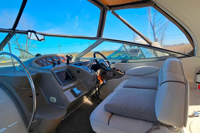 Slide: The Image of 2001 Maxum 3500 SCR boat interior with helm, gauges, and seating under clear blue sky. - 11