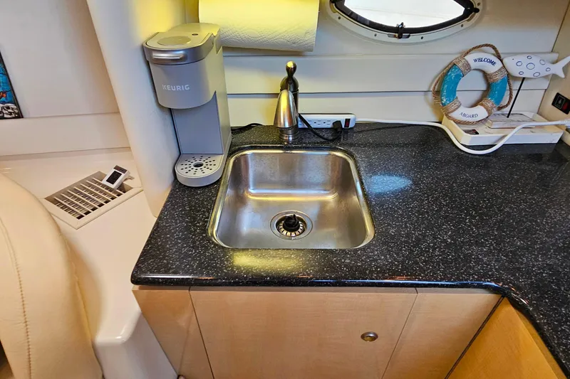 Slide: The Image of 2001 Maxum 3500 SCR yacht kitchenette with sink, Keurig coffee maker, and nautical decor. - 29