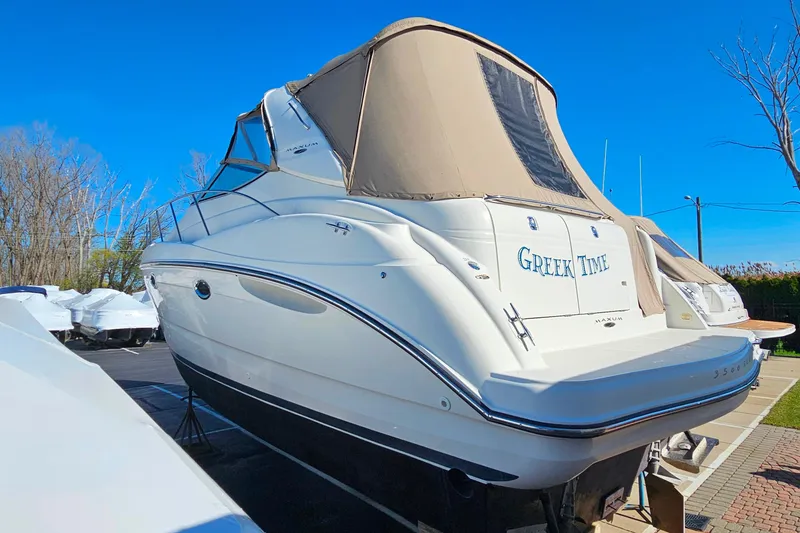 Slide: The Image of 2001 Maxum 3500 SCR boat with beige canopy, named "Greek Time," docked outdoors. - 3