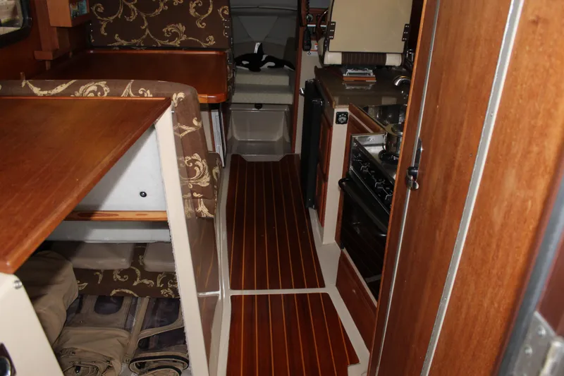 Slide: The Image of Interior of 2011 Ranger Tugs R-27 boat with wood finishes and compact kitchen area. - 28