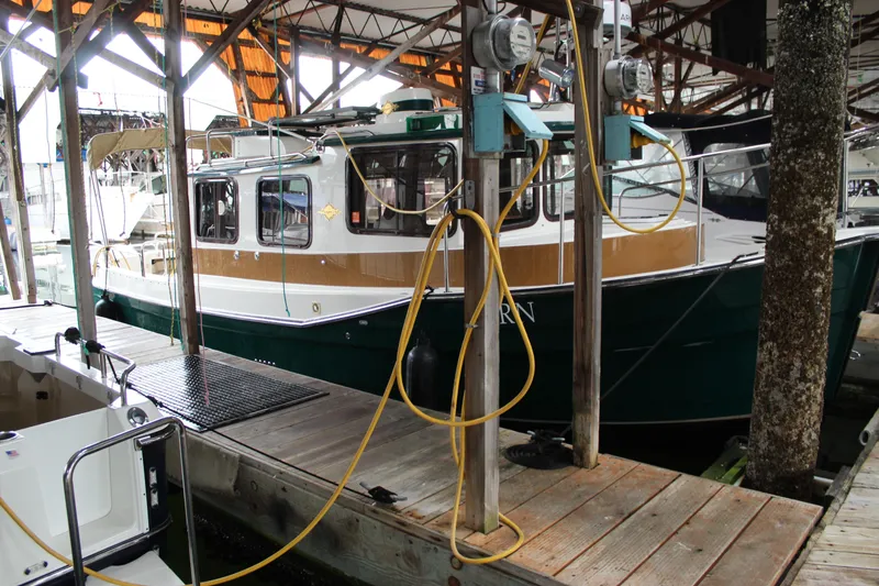 Slide: The Image of 2011 Ranger Tugs R-27 docked in a covered marina, surrounded by utility hookups. - 3
