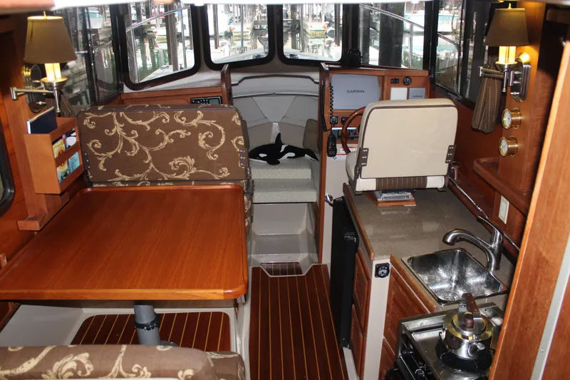 Slide: The Image of Interior of a 2011 Ranger Tugs R-27 boat with wood finishes and compact kitchen. - 30