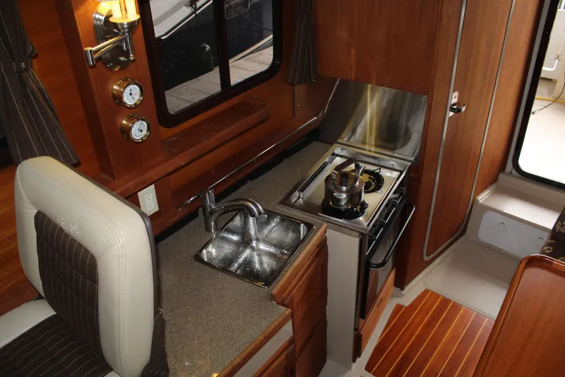 Slide: The Image of Interior of 2011 Ranger Tugs R-27 boat featuring compact kitchen with stove and sink. - 34