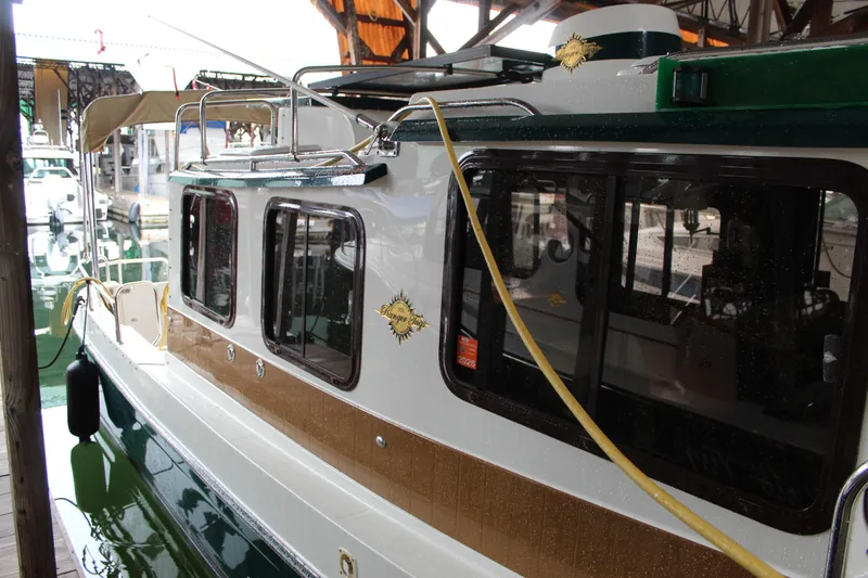 Slide: The Image of 2011 Ranger Tugs R-27 boat docked in a marina, showcasing its sleek design and windows. - 4