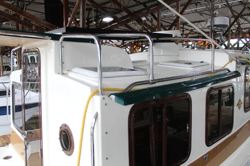 Slide: The Image of 2011 Ranger Tugs R-27 boat cabin with rooftop hatches and railing in a marina setting. - 7