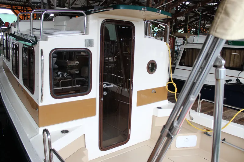 Slide: The Image of 2011 Ranger Tugs R-27 boat docked in a marina, showcasing its cabin entrance. - 9