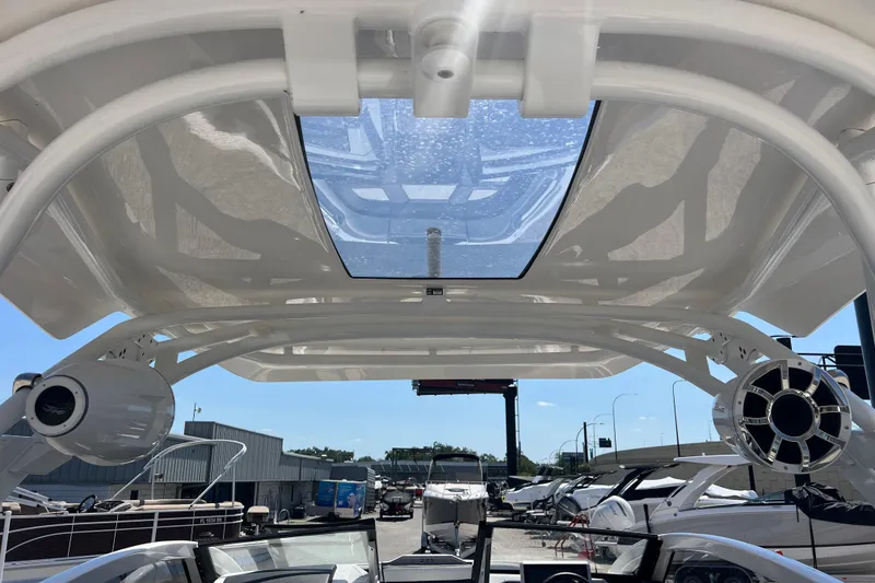 Slide: The Image of 2022 Yamaha 275 SD boat interior with speakers and sunroof at a marina. - 16