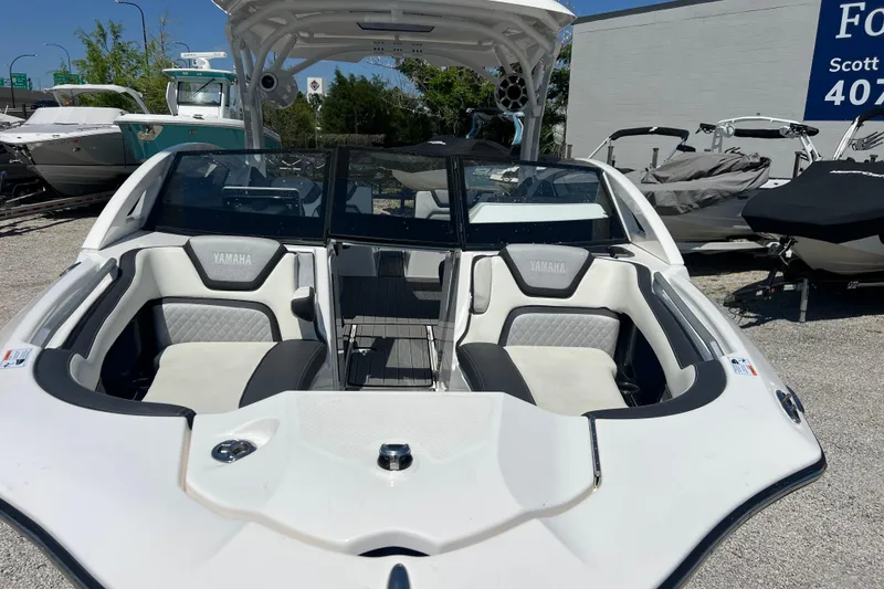 Slide: The Image of 2022 Yamaha 275 SD boat with sleek seating and modern design in a showroom. - 4