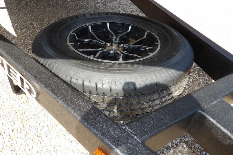 Slide: The Image of Spare tire on Crestliner 1860 Retriever CC trailer, 2026 model, resting on gravel. - 31