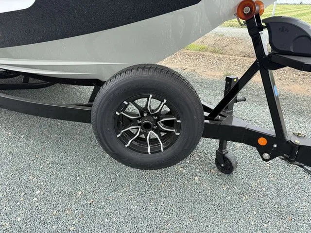 Slide: The Image of MasterCraft XT22 2026 boat trailer with black wheel on gravel. - 9