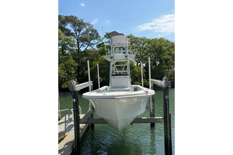 Slide: The Image of 2021 Pair Customs 24 Center Console MV boat on lift by water. - 2