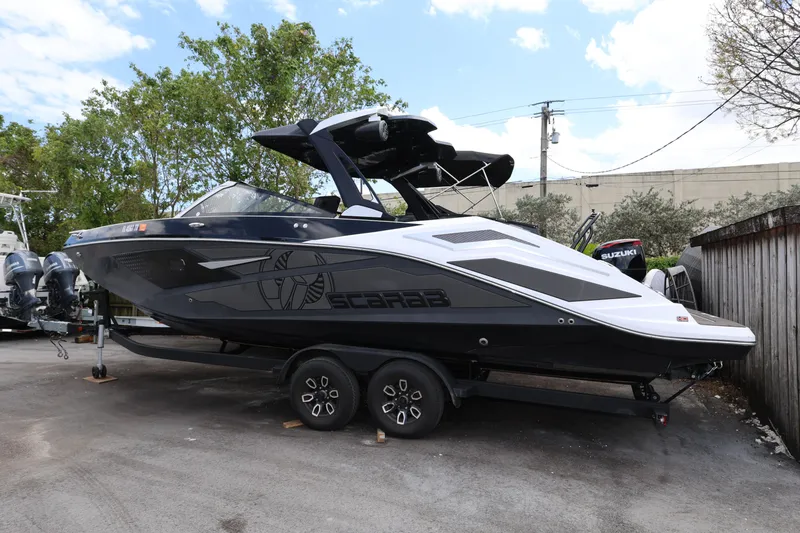 Slide: The Image of 2024 Scarab 285 ID boat on trailer, sleek design, parked outdoors. - 2