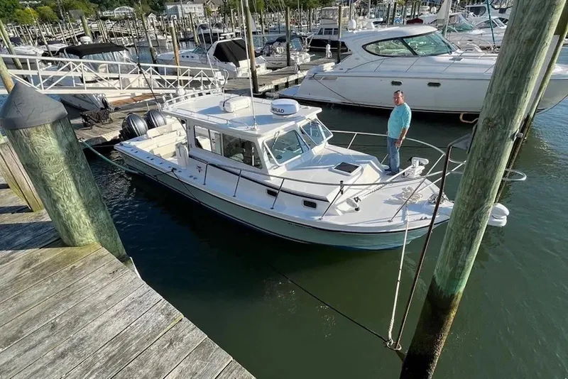 Slide: The Image of 2023 Steiger Craft 31 Fisherman docked at marina with person on deck. - 2