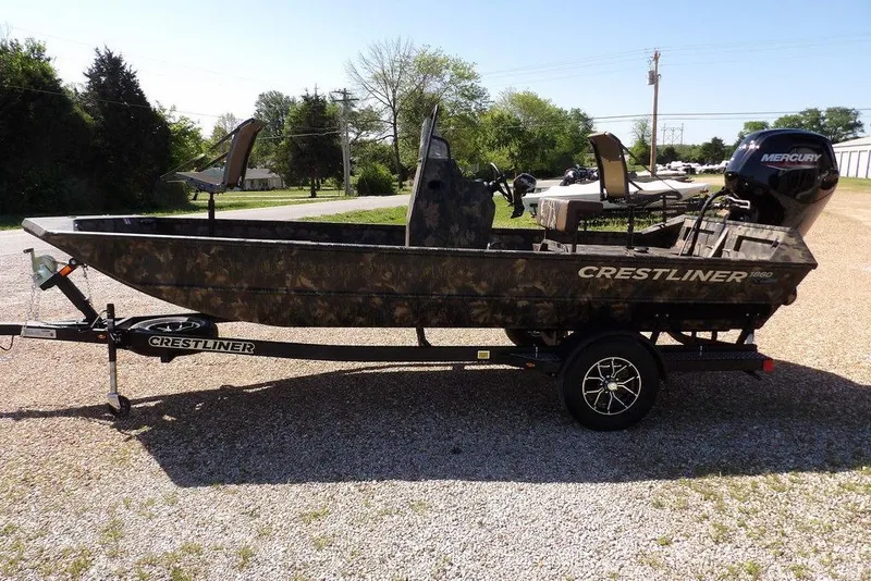 Slide: The Image of 2026 Crestliner 1860 Retriever CC Tunnel boat on trailer, camo design, parked outdoors. - 7