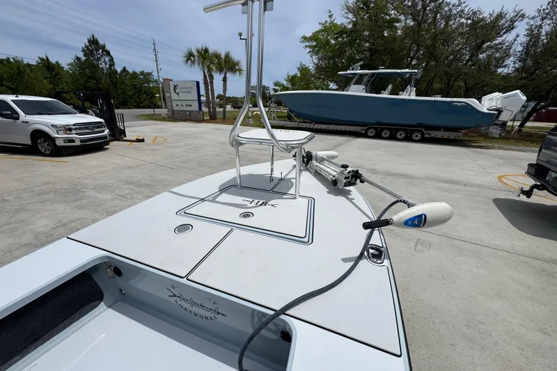 Slide: The Image of 2016 Hell's Bay Professional boat in a parking lot with nearby vehicles and trees. - 16