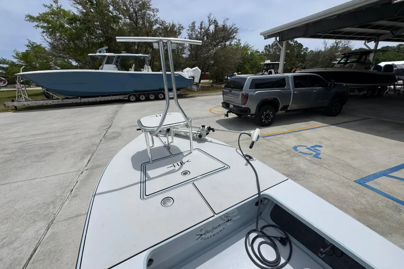 Slide: The Image of 2016 Hell's Bay Professional boat on trailer near parked truck and other boats. - 18