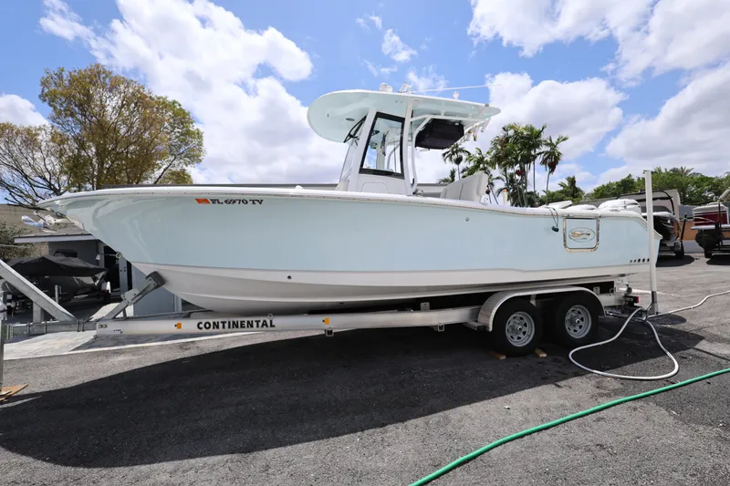 The Image of 2024 Sea Hunt Gamefish 25 boat on trailer, parked outdoors under a blue sky. - 0