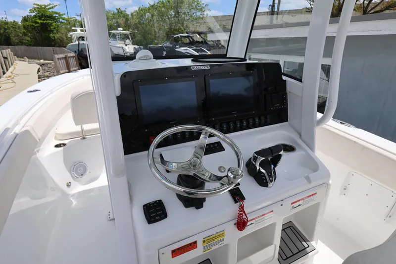Slide: The Image of 2024 Sea Hunt Gamefish 25 boat dashboard with steering wheel and navigation controls. - 12