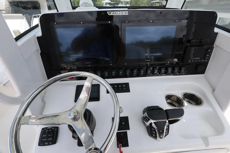 Slide: The Image of 2024 Sea Hunt Gamefish 25 helm with dual displays, steering wheel, and controls. - 13