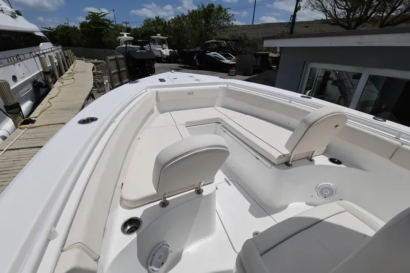 Slide: The Image of 2024 Sea Hunt Gamefish 25 boat interior with white seating and deck, docked outdoors. - 15