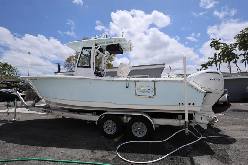 Slide: The Image of 2024 Sea Hunt Gamefish 25 boat on trailer, parked outdoors under a blue sky. - 2