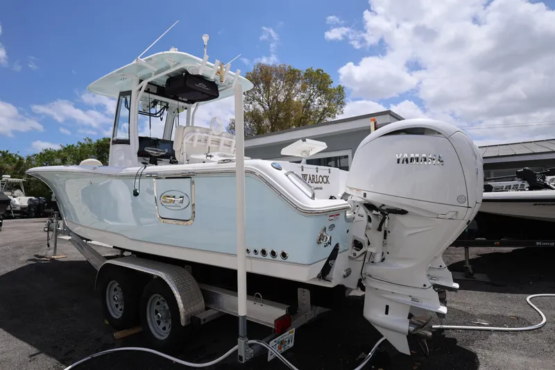 Slide: The Image of 2024 Sea Hunt Gamefish 25 boat on trailer with Yamaha outboard motor, under a partly cloudy sky. - 3
