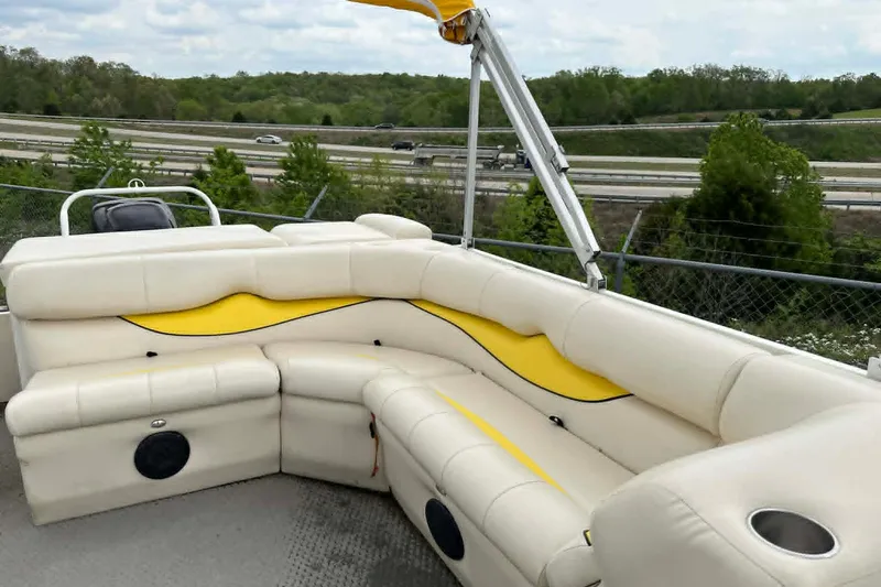 Slide: The Image of 2011 Bentley Pontoons 250/253 Elite Admiral with beige and yellow seating, parked near highway. - 2