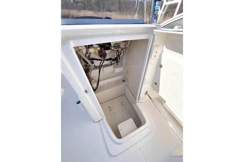 Slide: The Image of 2018 Robalo R180 Center Console storage compartment with visible wiring and open hatch. - 12