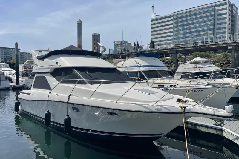 The Image of 1996 Bayliner 3255 Avanti yacht docked at marina with modern buildings in background. - 1