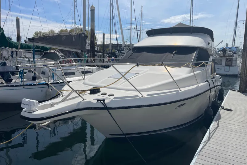 Slide: The Image of 1996 Bayliner 3255 Avanti docked at marina, surrounded by sailboats under clear sky. - 3