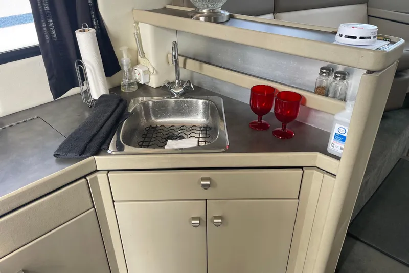 Slide: The Image of Compact kitchen area in a 1996 Bayliner 3255 Avanti boat with sink and red glasses. - 37