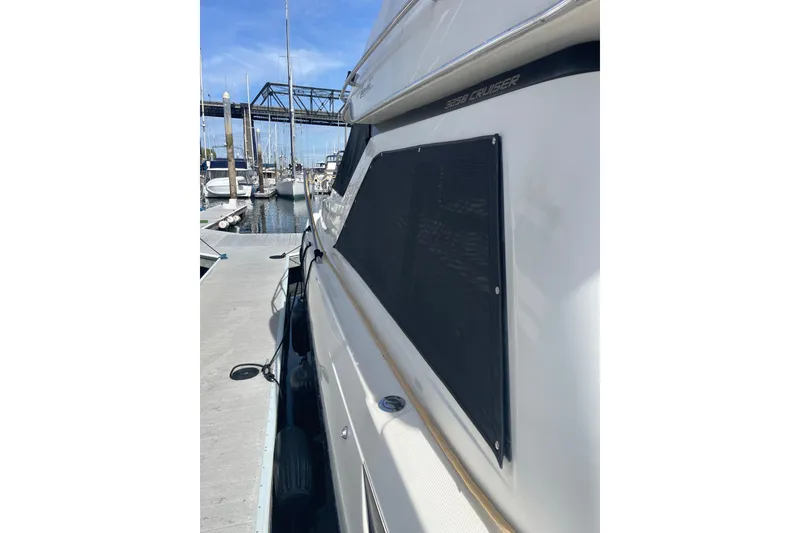 Slide: The Image of 1996 Bayliner 3255 Avanti docked at marina, side view with bridge in background. - 5