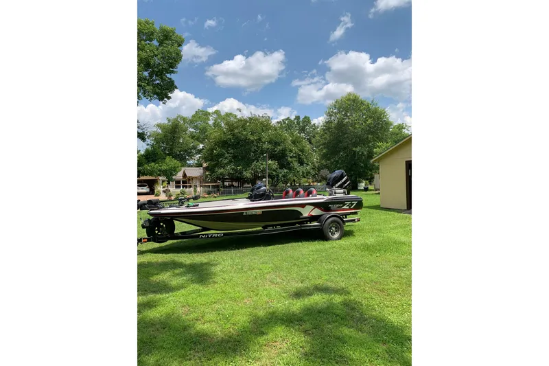 The Image of 2010 Nitro Z-7 boat on trailer, parked on grassy lawn under a partly cloudy sky. - 1