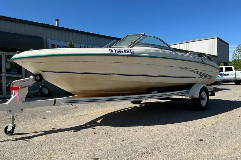 The Image of 1998 Sea Ray 175 Bow Rider boat on trailer, parked outside a dealership. - 1