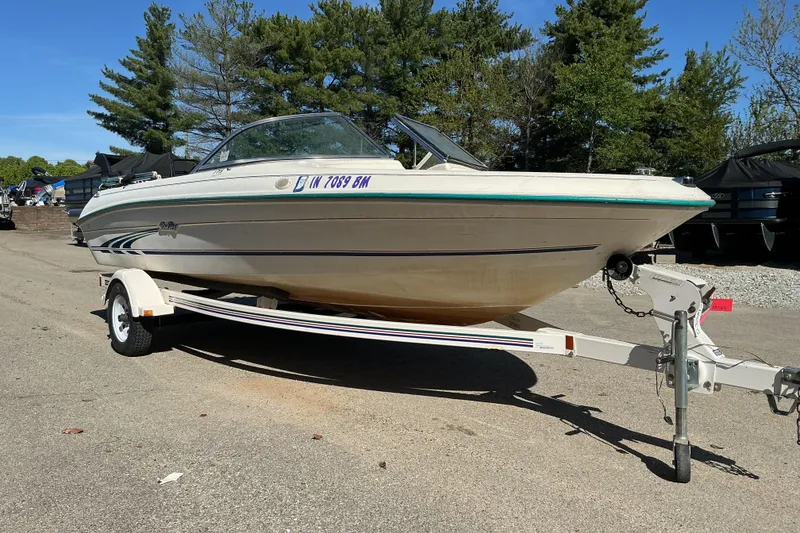 Slide: The Image of 1998 Sea Ray 175 Bow Rider boat on trailer, parked outdoors with trees in background. - 3