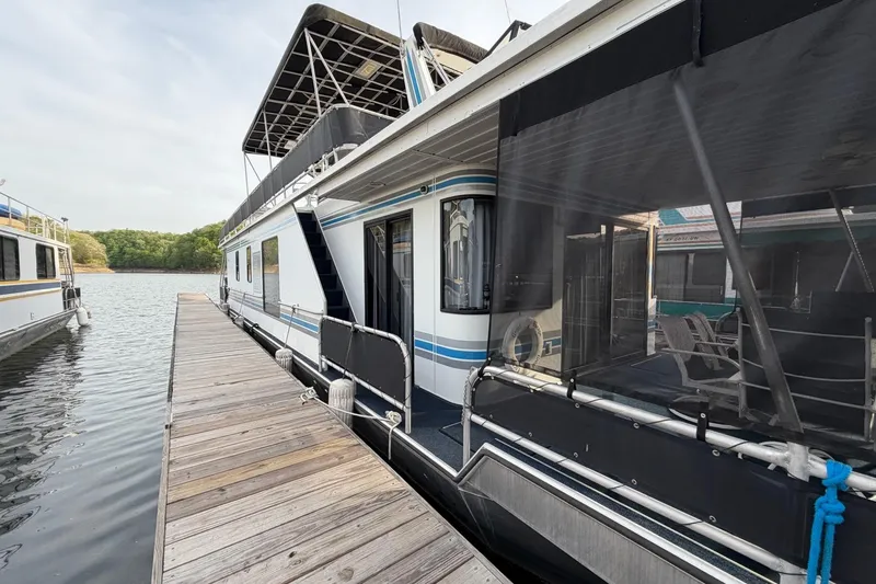 The Image of Houseboat docked on a lake, Sunstar 16x65 model, year 2000, with upper deck canopy. - 0