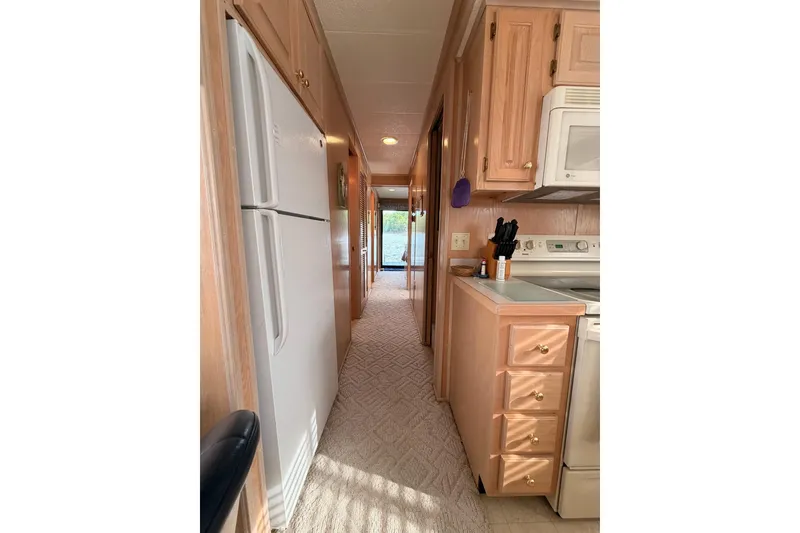 Slide: The Image of Narrow kitchen interior of 2000 Sunstar 16x65 houseboat with wooden cabinets and appliances. - 15