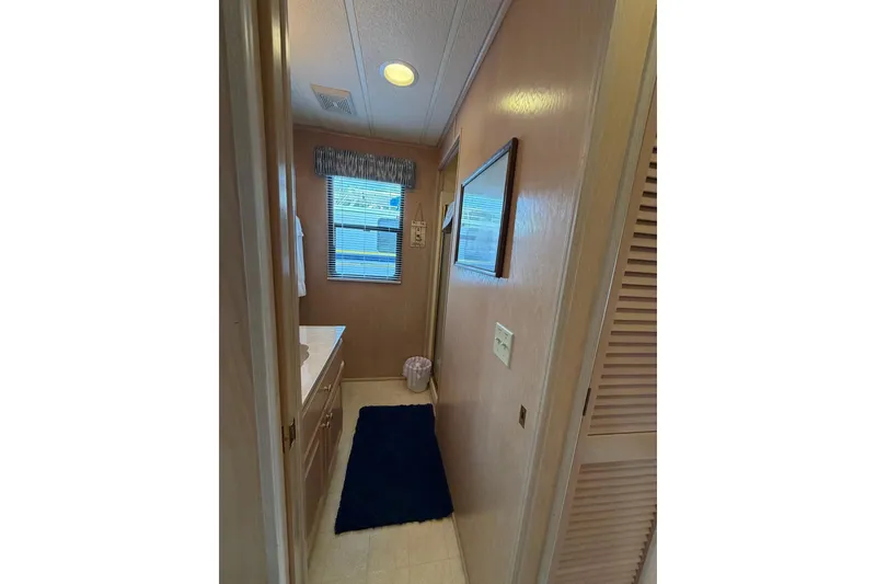 Slide: The Image of Narrow bathroom in 2000 Sunstar 16x65 houseboat with window and blue rug. - 18