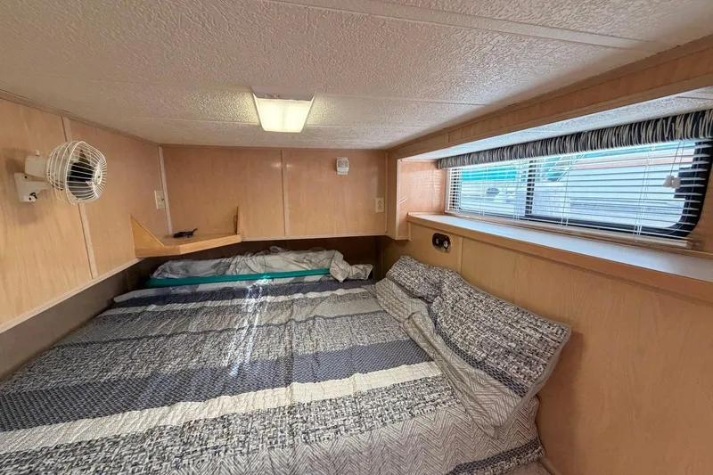 Slide: The Image of Cozy bedroom interior of 2000 Sunstar 16x65 houseboat with striped bedding and window blinds. - 24