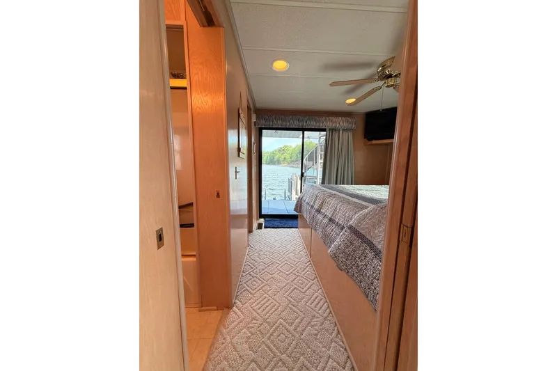 Slide: The Image of Interior of 2000 Sunstar 16x65 houseboat bedroom with lake view, ceiling fan, and cozy decor. - 27