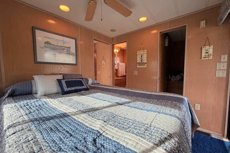 Slide: The Image of Cozy bedroom in a 2000 Sunstar 16x65 houseboat with nautical decor and quilted bedding. - 31